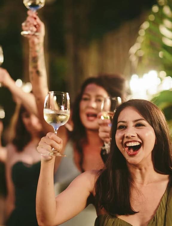 Group of women celebrating with wine glasses at an event.