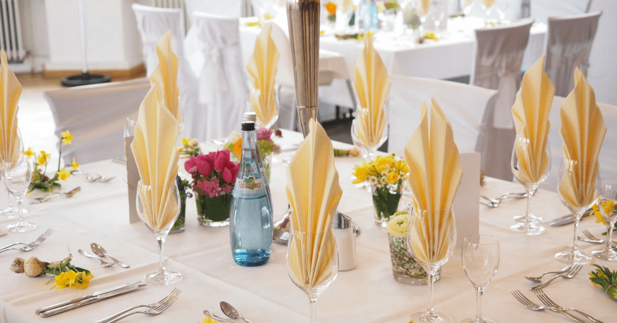 Beautifully arranged Maui catering table with yellow napkins and floral centerpieces.