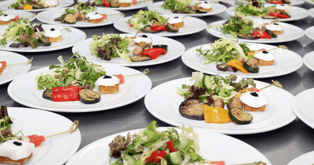 Assorted plated appetizers with fresh vegetables and sauces for catering events.