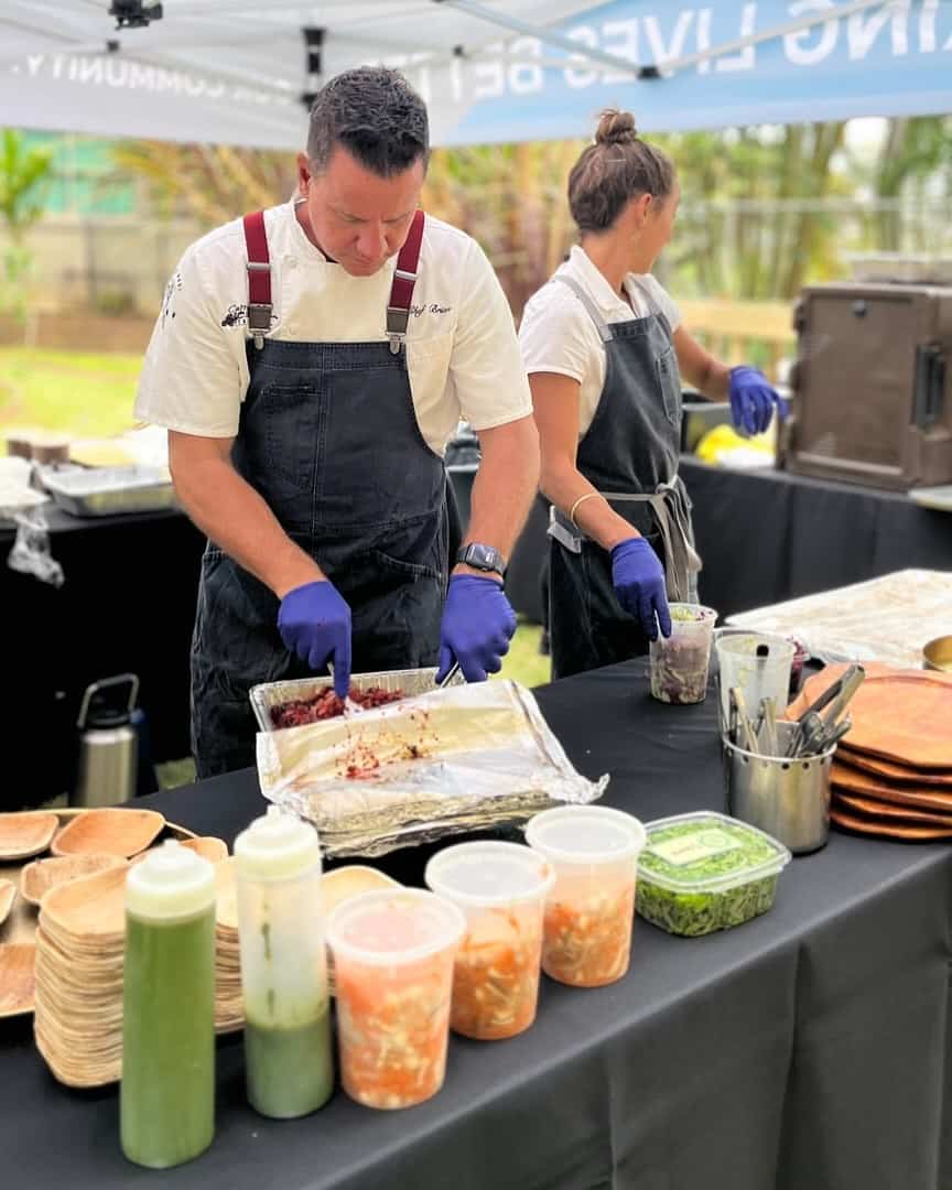 Catering staff preparing food at outdoor event with fresh ingredients and utensils.